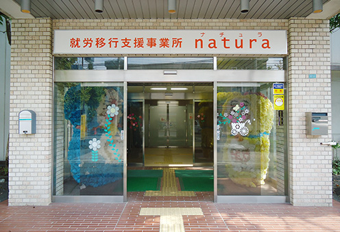 natura入口の写真、足元の点字ブロック、自動ドアが映っている